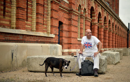 A man sits with his dog outside the Copper Rivet Distillery in Chatham, Britain, August 8, 2017. Picture taken August 8, 2017. REUTERS/Hannah McKay