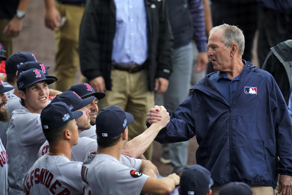 Former President George W. Bush, right, visits with Boston Red Sox players as he walks past their dugout during pre-game festivities before the MLB Little League Classic baseball game between the Baltimore Orioles and the Boston Red Sox in Williamsport, Pa., Sunday, Aug. 21, 2022. (AP Photo/Gene J. Puskar)