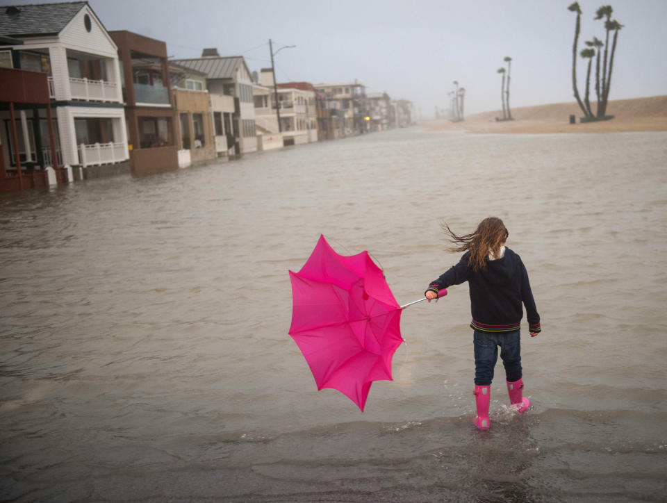 Isabella Busse , 6, walks through floodwater near the Seal Beach Pier during a storm in Seal Beach, Calif., Sunday, Jan. 22, 2017. The heavy downpour on Sunday drenched Orange County in one of the heaviest storms of the year. Fast-moving floodwaters swept through California mountain communities and residents fled homes below hillsides scarred by wildfires as the third in the latest series of storms brought a deluge Sunday and warnings about damaging mudslides. (Ana Venegas/The Orange County Register via AP)