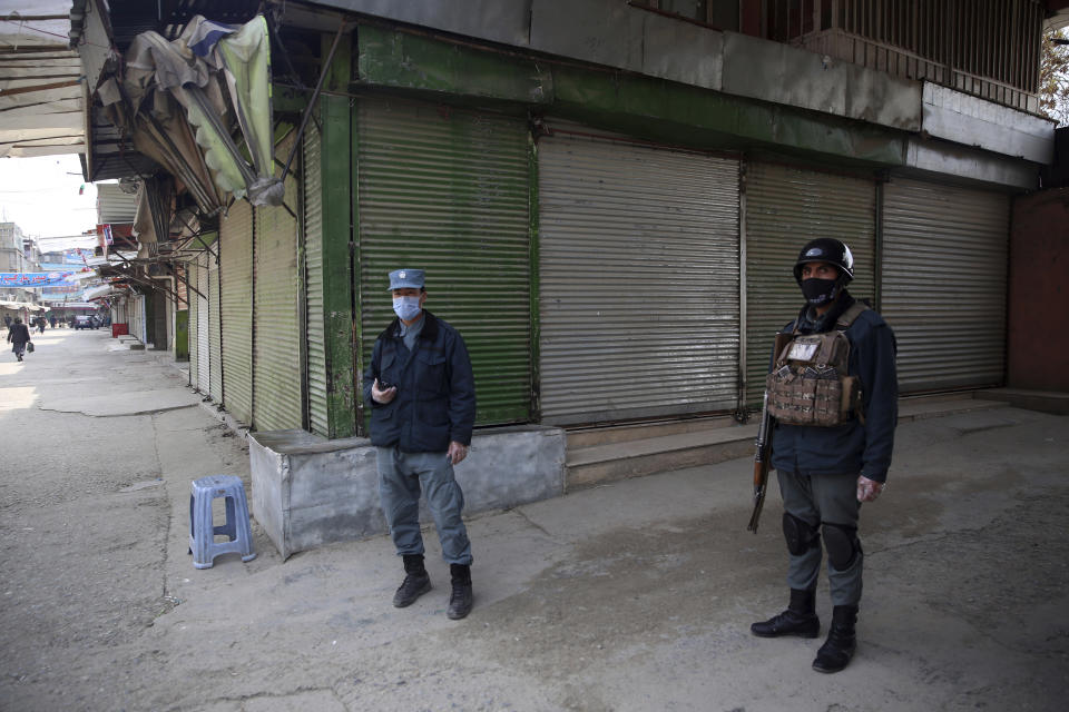 Police officers guard shuttered storefronts following a lockdown amid concern over spread of coronavirus in Kabul, Afghanistan, Sunday, March 29, 2020. The Afghan government Friday ordered a three-week lock-down for Kabul to stem the spread of the virus. (AP Photo/Rahmat Gul)
