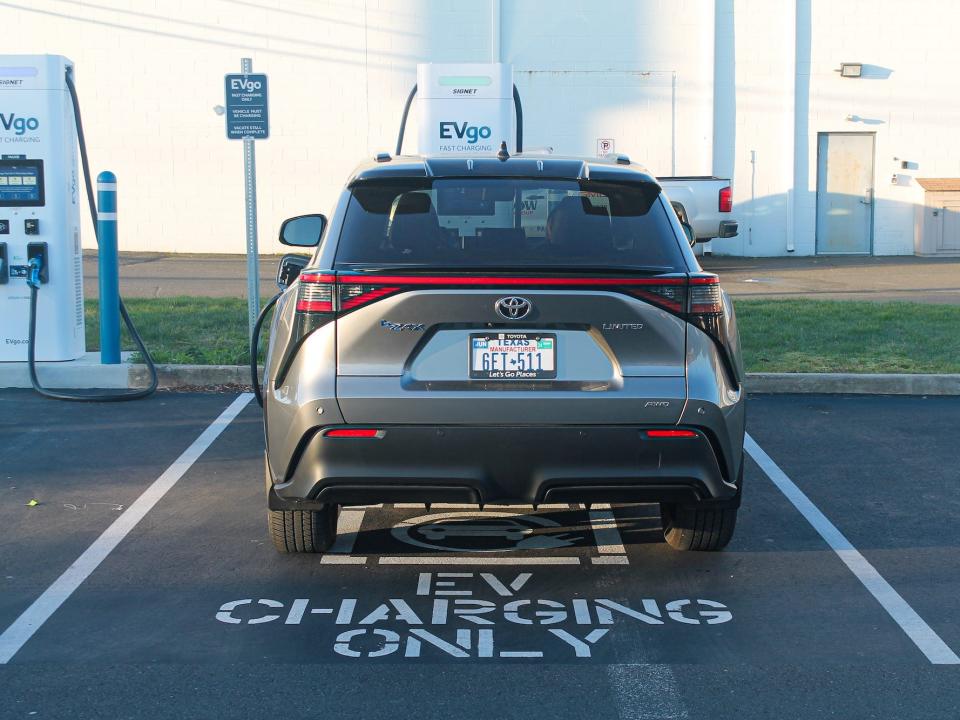 A silver 2023 Toyota bZ4X AWD Limited at a charging station, from the rear.