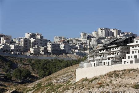 A construction site is seen in Pisgat Zeev (R), an urban settlement in an area Israel annexed to Jerusalem after capturing it in the 1967 Middle East war, as the Shuafat refugee camp (rear) in the West Bank is seen behind a section of the controversial Israeli barrier, July 28, 2013. REUTERS/Baz Ratner