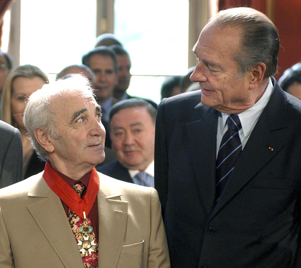 FILE - In this May 14, 2004 file photo, then French President Jacques Chirac chats with French singer Charles Aznavour after making him commander of the Legion of Honor, France's prestigious honor, during a ceremony at the Elysee Palace in Paris. Charles Aznavour, the French crooner and actor whose performing career spanned eight decades, has died. He was 94. (AP Photo/Remy de la Mauviniere, File)