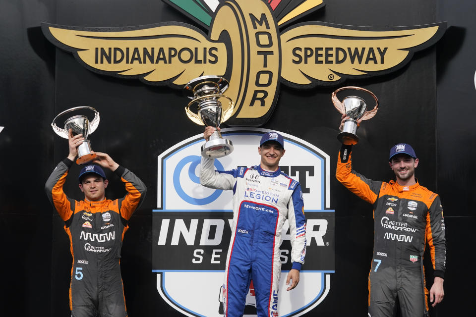 Alex Palou, center, of Spain, holds the trophy after winning the IndyCar Grand Prix auto race at Indianapolis Motor Speedway, Saturday, May 13, 2023, in Indianapolis. Pato O'Ward, left, of Mexico, finished second, and Alexander Rossi finished third. (AP Photo/Darron Cummings)