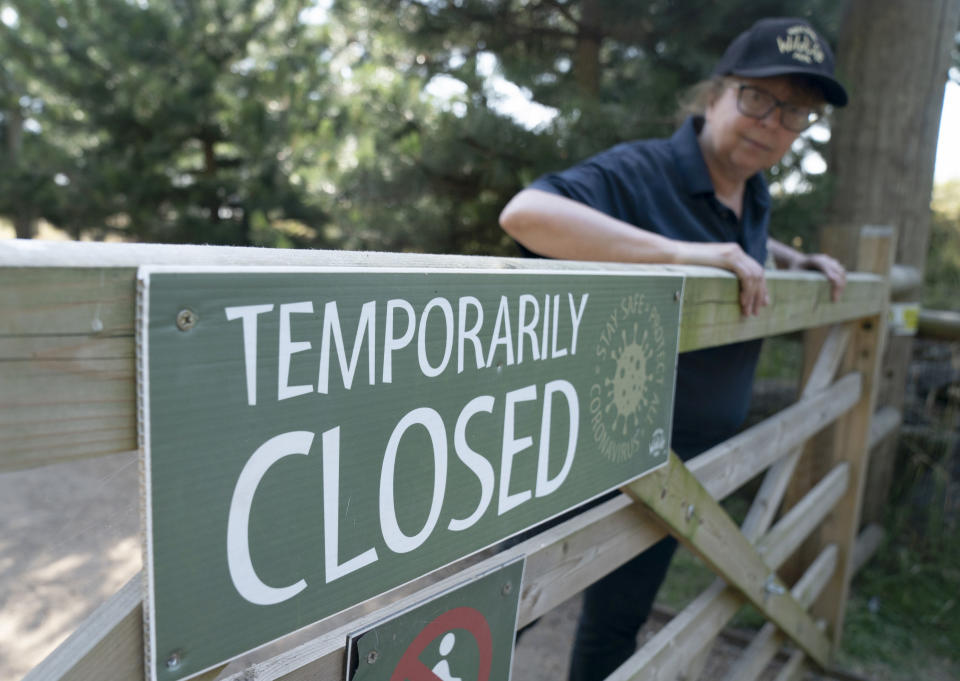An employee stands by a gate at the Yorkshire Wildlife Park in Doncaster, which is temporarily closed due to the hot weather as record temperatures hit the UK, Monday July 18, 2022. Britain’s first-ever extreme heat warning is in effect for large parts of England as hot, dry weather that has scorched mainland Europe for the past week moves north, disrupting travel, health care and schools. (Danny Lawson/PA via AP)