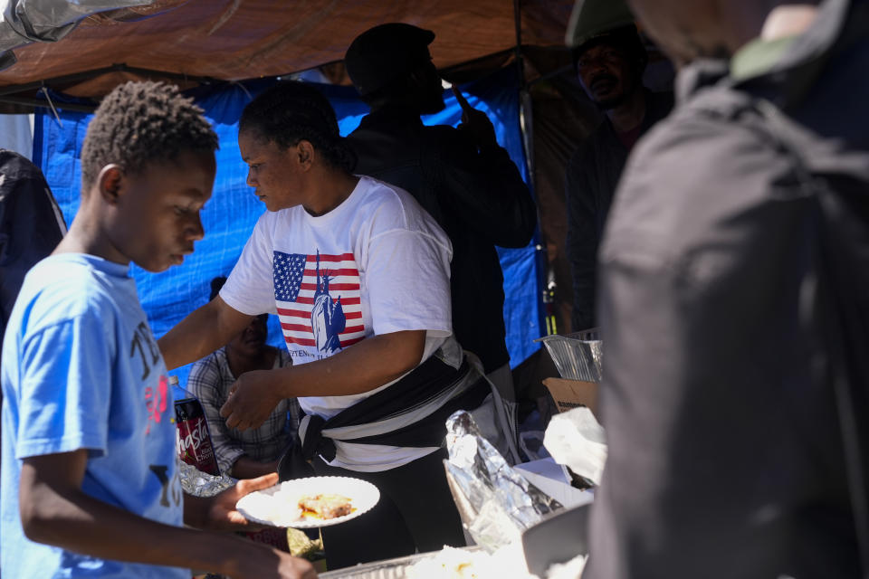 Monique Mupepe, from Congo, helps serve donated food at an encampment of asylum-seekers mostly from Venezuela, Congo and Angola next to an unused motel owned by the county, Wednesday, June 5, 2024, in Kent, Washington. The group of about 240 asylum-seekers is asking to use the motel as temporary housing while they look for jobs and longer-term accommodations. (AP Photo/Lindsey Wasson)