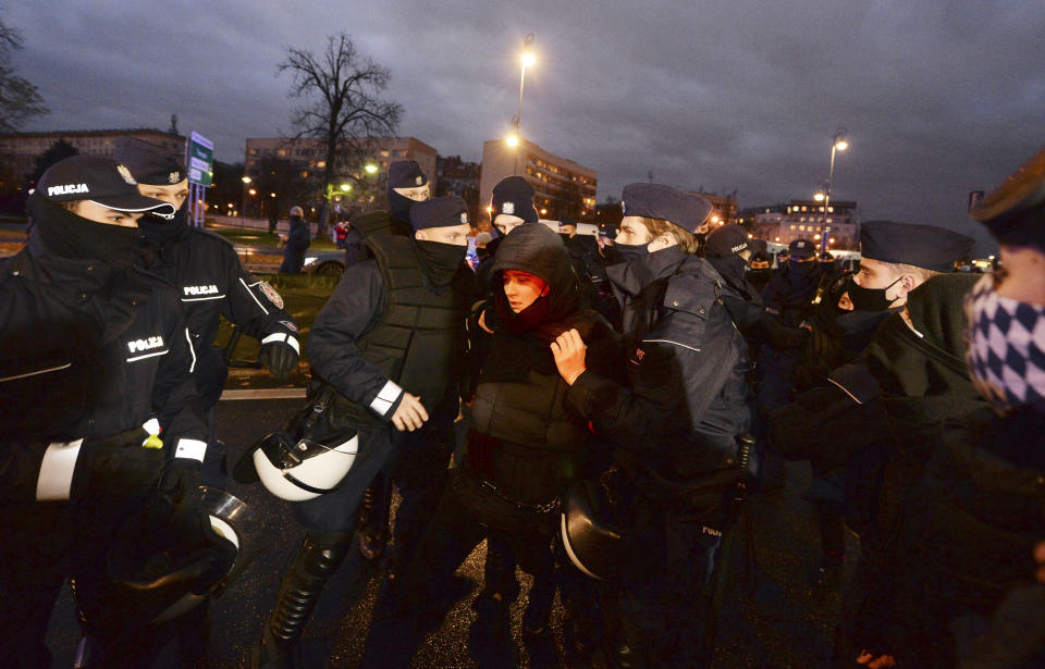 Police confront protesters in front of the Education Ministry building in Warsaw, Poland, on Monday Nov. 23, 2020. Police detained several people as women-led protests over abortion rights flared up in Warsaw and elsewhere in Poland. The protests, organized by the group Women's Strike, have been occurring regularly since the constitutional court issued an Oct. 22 ruling that further tightens an abortion law that was already one of the most restrictive in Poland.(AP Photo/Czarek Sokolowski)