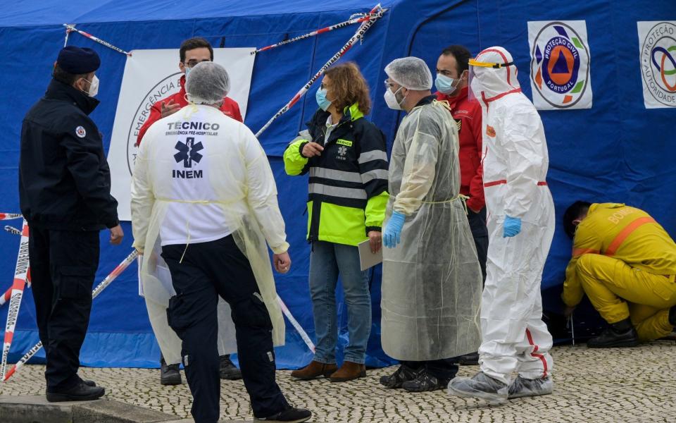 Healthcare workers in PPE stand outside a Civil Protection tent in the new pre-triage and triage area for COVID-19 at Santa Maria Hospital, Lisbon. -  Horacio Villalobos / Corbis via Getty