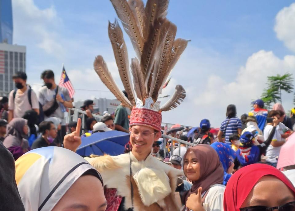 A man in an Iban costume posing with a woman during the National Day parade in Malaysia on the 31st of August 2022. (Photo: Yahoo Singapore)