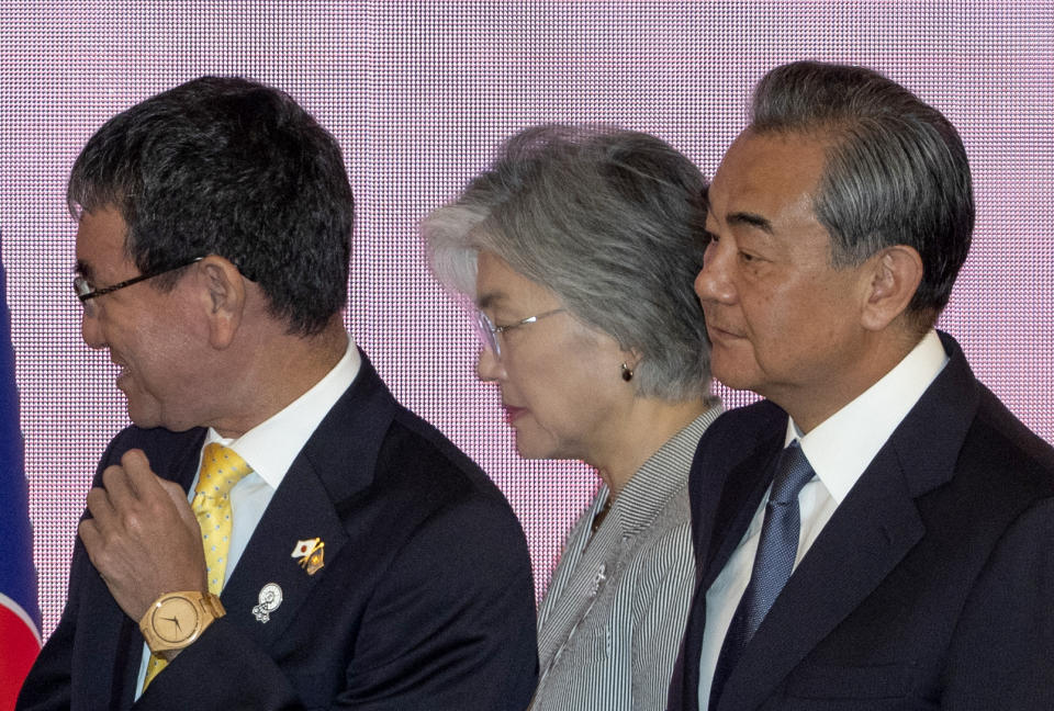 Foreign Ministers from left, Japan's Foreign Minister Taro Kono, South Korea's Foreign Minister Kang Kyung-wha and China's Foreign Minister Wang Yi walk back after posing for group photo during the Association of Southeast Asian Nations Plus Three meeting in Bangkok, Thailand, Friday, Aug. 2, 2019. (AP Photo/Gemunu Amarasinghe)