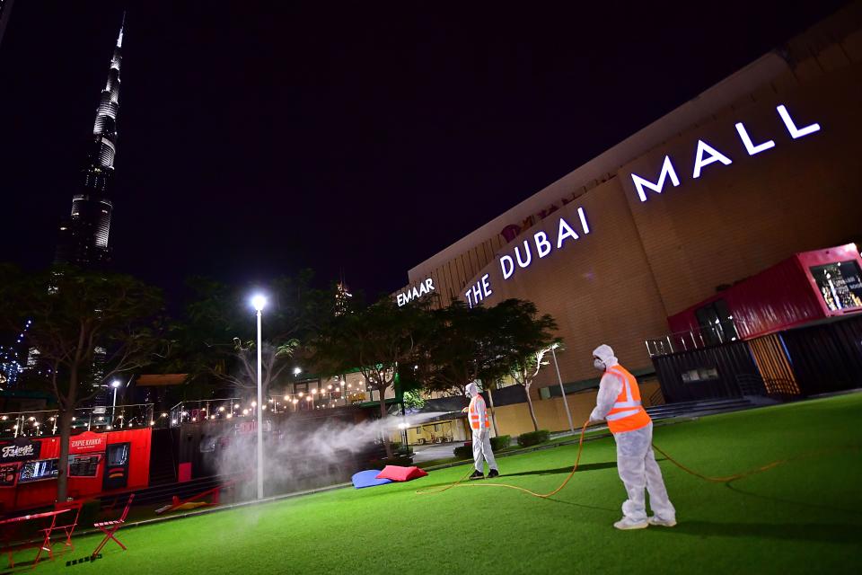 Dos trabajadores desinfectan los alrededores del Dubai Maill y el Burj Khalifa de Dubái (Emiratos Árabes Unidos) el 27 de marzo. (Foto: Giuseppe Cacace / AFP / Getty Images).