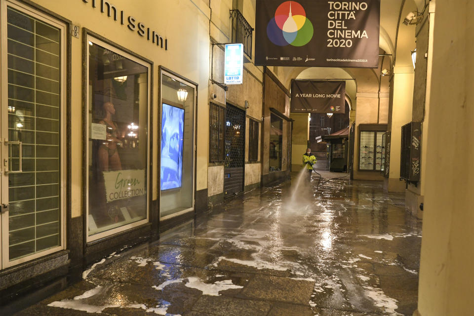 An operator sanitizes streets and sidewalk in Turin, Italy, in the early hours of Saturday, March 14, 2020. A sweeping lockdown is in place in Italy to try to slow down the spread of coronavirus epidemic. For most people, the new coronavirus causes only mild or moderate symptoms. For some, it can cause more severe illness, especially in older adults and people with existing health problems. (Fabio Ferrari/LaPresse via AP)