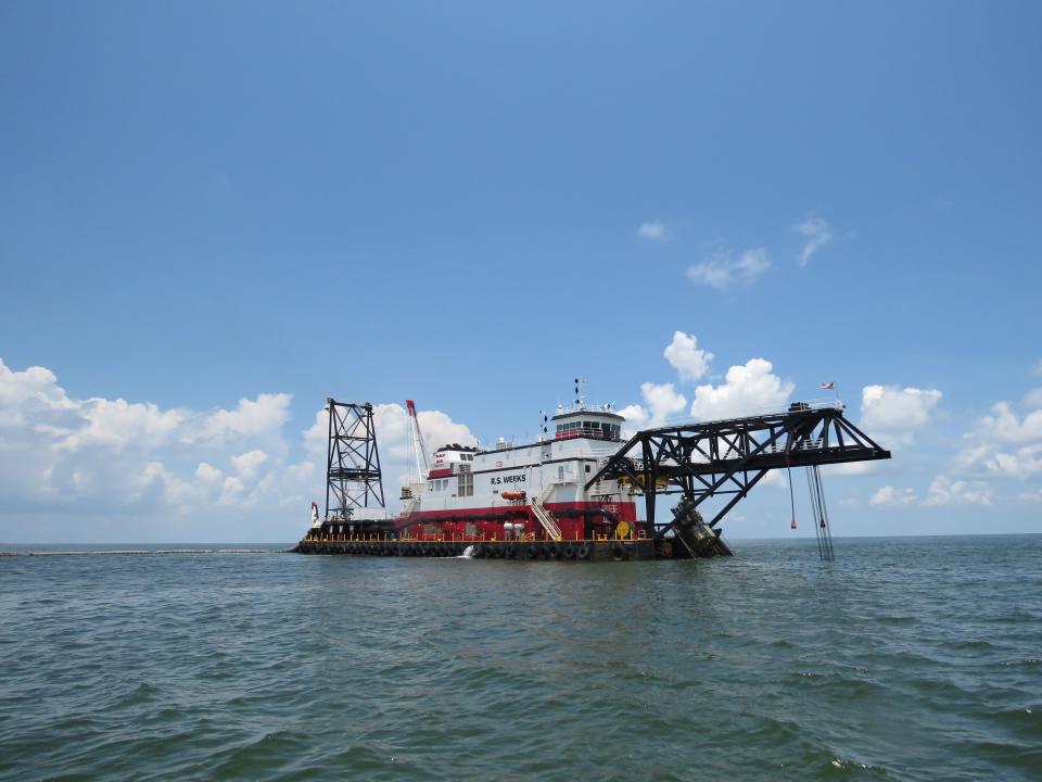 The cutter head dredge R.S. Weeks pumps sand and water from the Gulf of Mexico to a Louisiana barrier island five miles away on Wednesday, July 28, 2021. The flexible pipe on the surface to its left connects to rigid pipe on the bottom. Contractors are at work on a $102 million Louisiana Coastal Restoration and Protection Authority project to add about 400 acres of beach, dune and marshland to Grand Terre Island. Weather permitting, they hope to finish in November. (AP Photo/Janet McConnaughey)