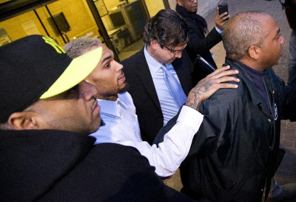 Singer Chris Brown is surrounded by bodyguards as he departs the H. Carl Moultriel courthouse Monday, Oct. 28, 2013, with one of his attorney's, Danny Onorato, center,, in Washington. A charge against the Grammy Award-winning R&B singer has been reduced to a misdemeanor and he was ordered released after his arrest Sunday following an altercation outside a Washington hotel. (AP Photo/ Evan Vucci)