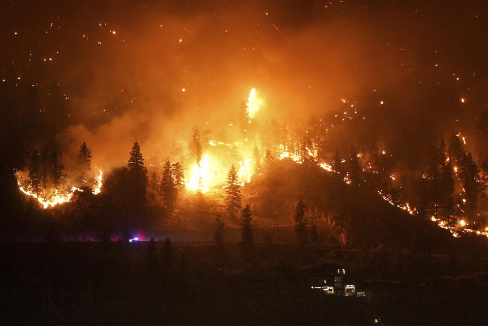 The McDougall Creek wildfire burns on the mountainside above a lakefront home in West Kelowna, Canada on Friday, Aug. 18, 2023. (Darryl Dyck/The Canadian Press via AP)