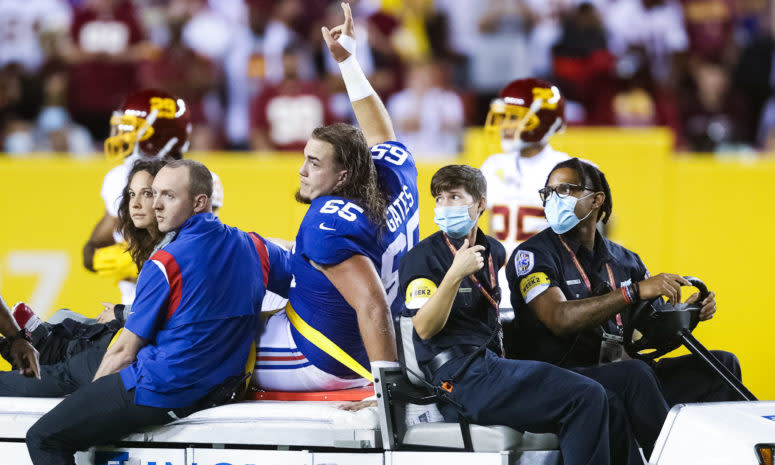 Giants center Nick Gates waves to fans as he is carted off the field.
