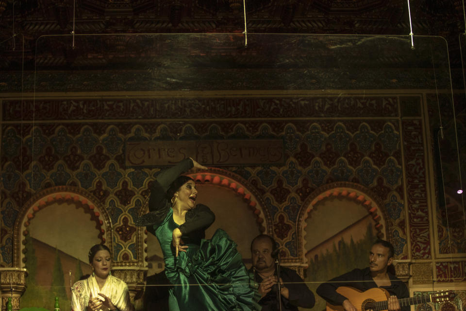 Flamenco dancer Antonia Estepa performs behind screens next to hand clappers and guitarists during a flamenco show at the Torres Bermejas "tablao," or live flamenco venue, in Madrid, Spain, Friday, Sept. 25, 2020. The passion and drama of live flamenco shows are back on stage in Madrid. But now the performers are behind Perspex screens and keeping their distance from the audience. The Torres Bermejas “tablao,” or live flamenco venue, has reopened its doors to customers after seven months closed due to the COVID-19 pandemic. (AP Photo/Manu Fernandez)