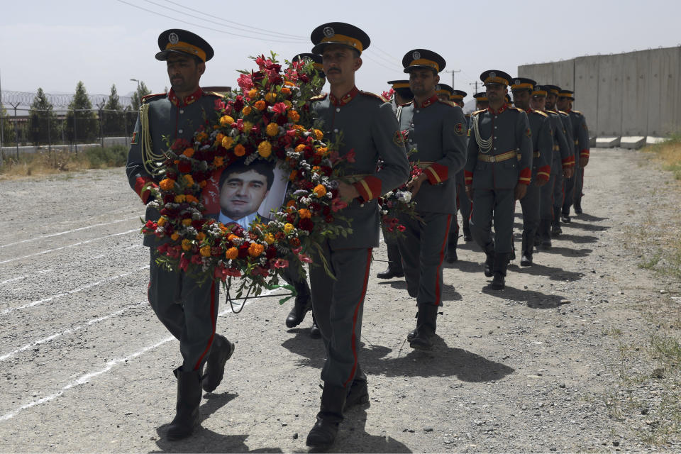 Afghan honor guards hold a wreath of flowers with a portrait of Dawa Khan Menapal, director of Afghanistan's Government Information Media Center, in Kabul, Afghanistan, Saturday, Aug. 7, 2021. The Taliban shot and killed the director of Afghanistan's Government Information Media Center on Friday, the latest killing of a government official and one that comes just days after an assassination attempt on the acting defense minister. (AP Photo/Rahmat Gul)