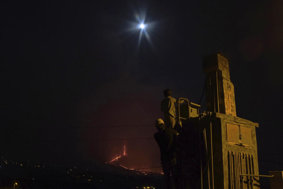 People look across to a volcano as it continues to erupt on the Canary island of La Palma, Spain on Saturday Oct. 16, 2021. Officials say there is no sign that a volcanic eruption on the Spanish island of La Palma is coming to an end, one month after it began. The volcano on one of the Canary Islands off northwest Africa has so far destroyed more than 1,800 buildings, mostly homes. (AP Photo/Daniel Roca)