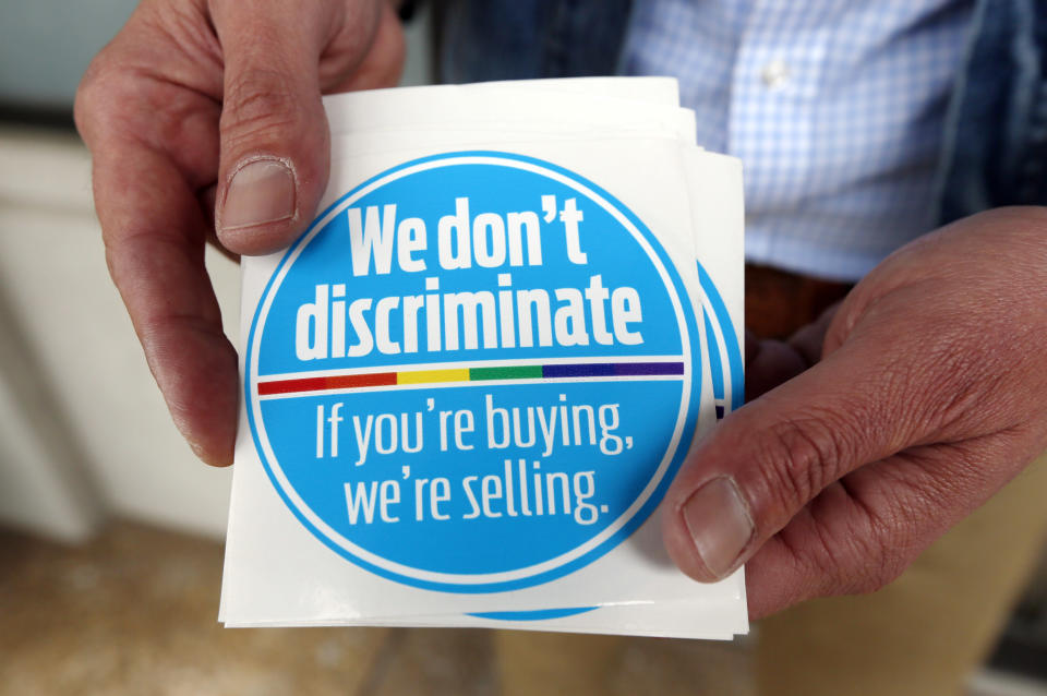 Eddie Outlaw, a Jackson hair salon owner, displays the stickers he and some other business owners display and have distributed to others in a show of support for gay and lesbian customers, Tuesday, April 22, 2014, outside his business in Jackson, Miss. The group sees this as an effort to push back against a religious-practices bill recently signed by Republican Gov. Phil Bryant. The round, blue window stickers declare: “We don’t discriminate. If you’re buying, we’re selling." (AP Photo/Rogelio V. Solis)