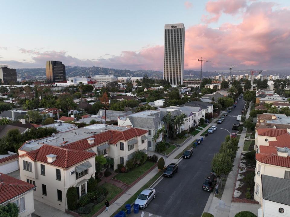 A residential neighborhood full of two-story buildings, with office towers in the distance.