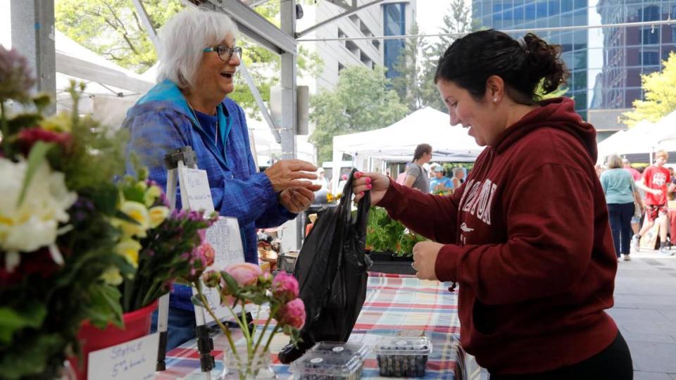 Beth Tillery, left, of Home Pickins Farm laughs in conversation with Daphne Hale, right, after Hale bought blueberries on Saturday, June 17, 2023, at the Fifth Third Pavilion in Lexington, Ky.