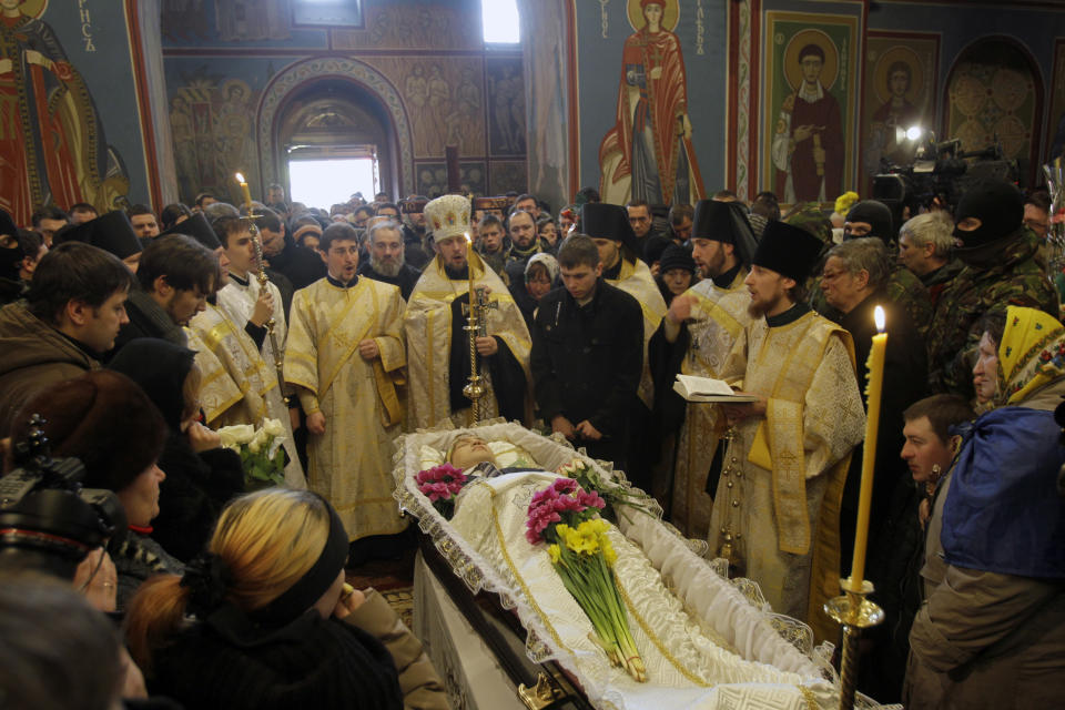 Orthodox Church priests perform a service to commemorate Mikhail Zhiznevsky, 25, one of two protesters who died of gunshot wounds on Wednesday, in Kiev, Ukraine, Sunday Jan. 26, 2014. Ukraine's opposition called off a massive rally planned for Sunday because of the funeral for a protester killed in clashes with police last week, underscoring the rising tensions in the country's two-month political crisis. The opposition contends they were shot by police in an area where demonstrators had been throwing rocks and firebombs at riot police for several days. (AP Photo/Darko Vojinovic)