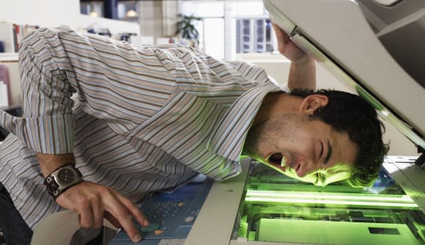 Male office worker photocopying side of face, mouth open, eyes closed