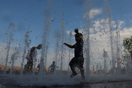 Children play in a water feature in Domino Park as a heatwave continued to affect the region in Brooklyn, New York City
