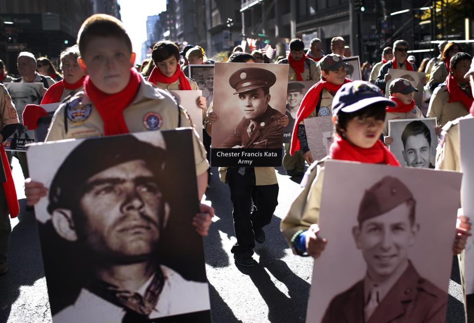 Cub Scouts carry photographs of World War II veterans as they march in the New York City Veterans Day parade on 5th Avenue in New York