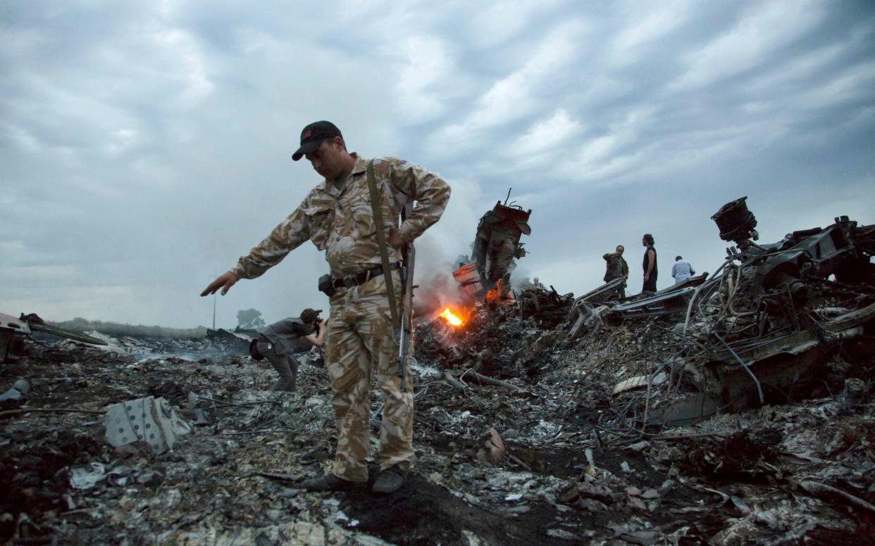 In this July 17, 2014 file photo, people walk amongst the debris at the crash site of MH17 - AP