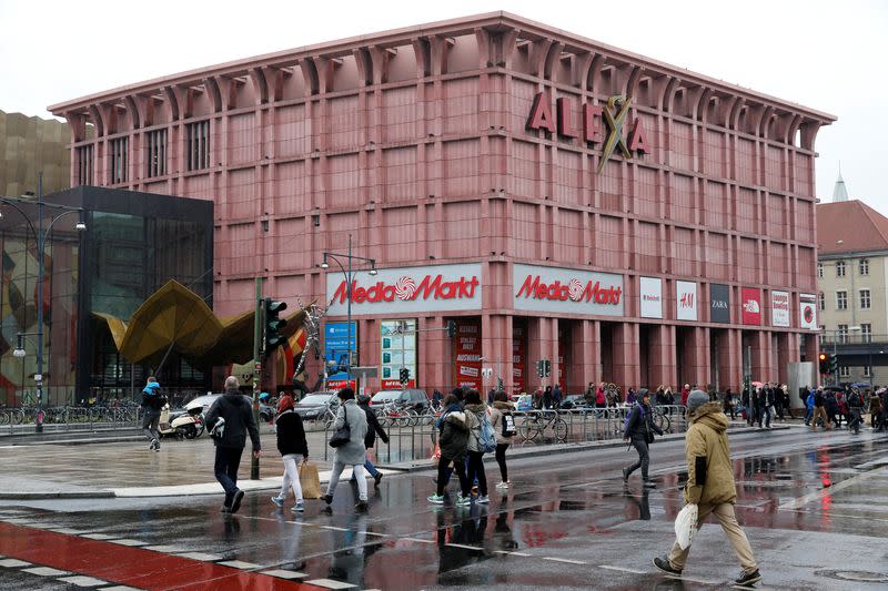 People walk next to Alexa shopping mall at Alexanderplatz in Berlin