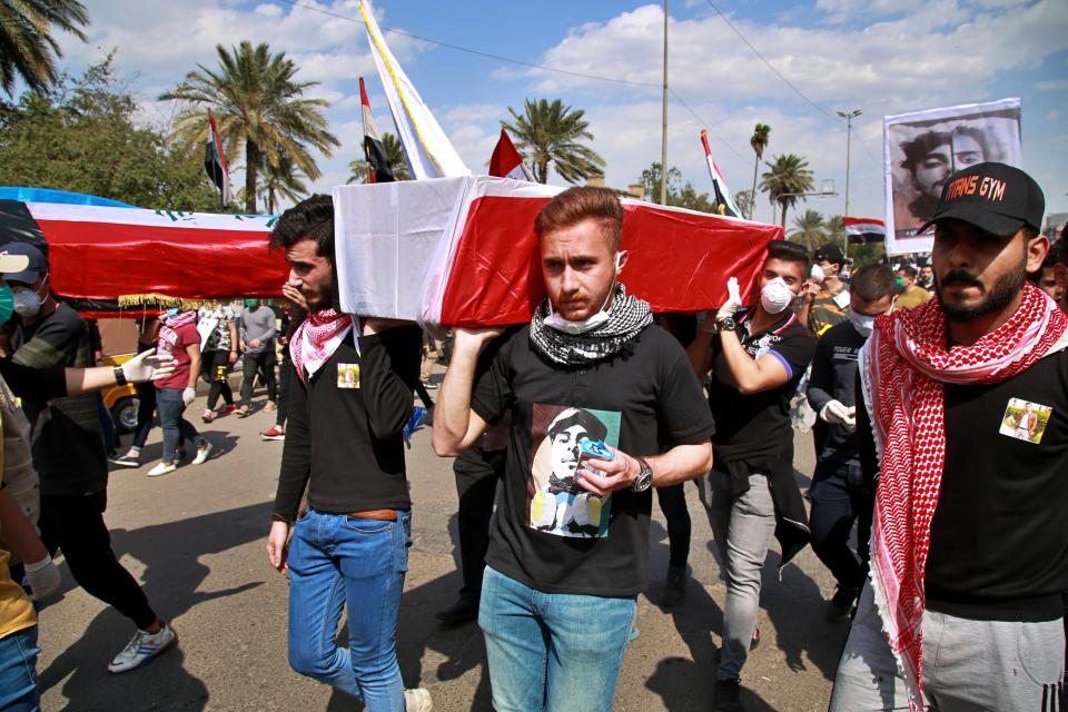 Protesters carry symbolic Iraqi flag-draped coffins and posters for people who have been killed in anti-government protests, during a rally in Baghdad, Iraq, Sunday, March 1, 2020. Iraqi student protesters converged on Baghdad's Tahrir Square, the epicenter of the five-month- anti-government protest movement, to voice their rejection of Allawi. (AP Photo/Khalid Mohammed)