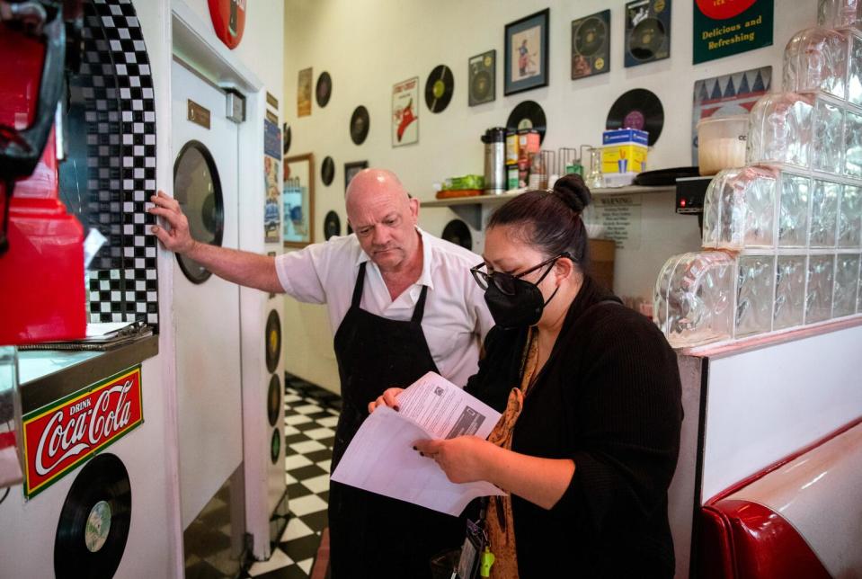 The Great Grill chef George Martin, left, looks over updated COVID-19 safety information with Ngoc McShane.