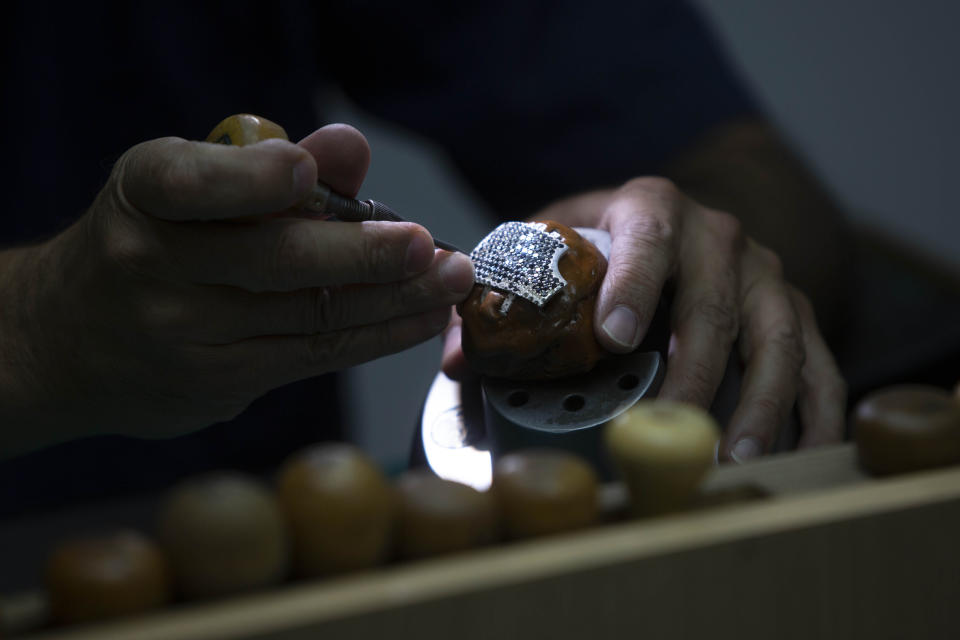 A worker for the Israeli jewelry company Yvel holds a part of a mask in Motza near Jerusalem, Sunday, Aug. 9, 2020. An Israeli jewelry company is working on what it says will be the world's most expensive coronavirus mask, a gold, diamond-encrusted face covering with a price tag of $1. 5 million. (AP Photo/Sebastian Scheiner)