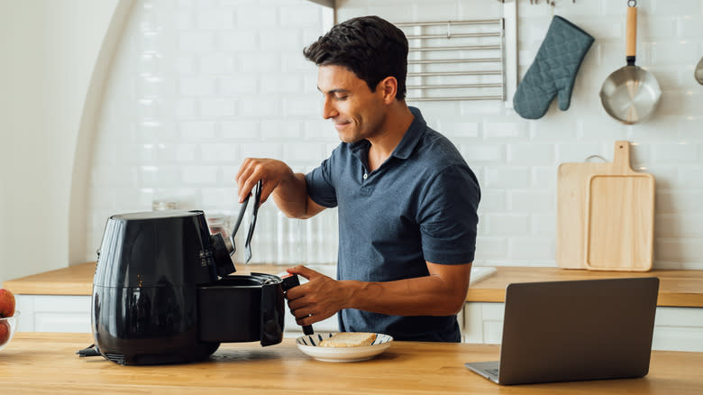 A man taking food out of an air fryer