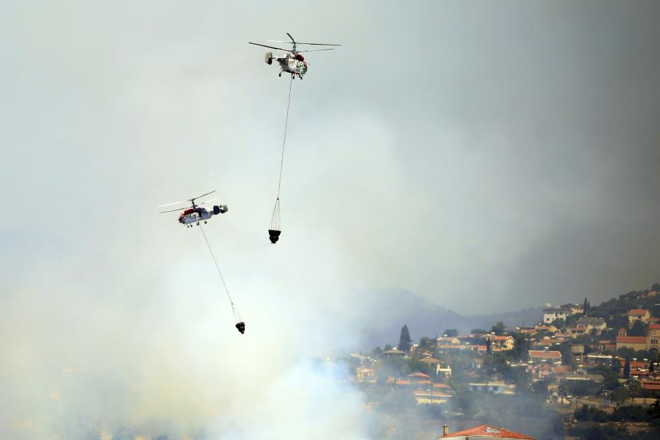 Two helicopters operate over a fire in Apesia semi-mountainous village near Limassol, southwestern Cyprus, Monday, Aug. 7, 2023. Greece on Monday dispatched two Canadair fire-fighting aircraft after a call for assistance from fellow European Union member Cyprus to help fight a blaze that has scorched miles of mountainous terrain. (AP Photo/Philippos Christou)