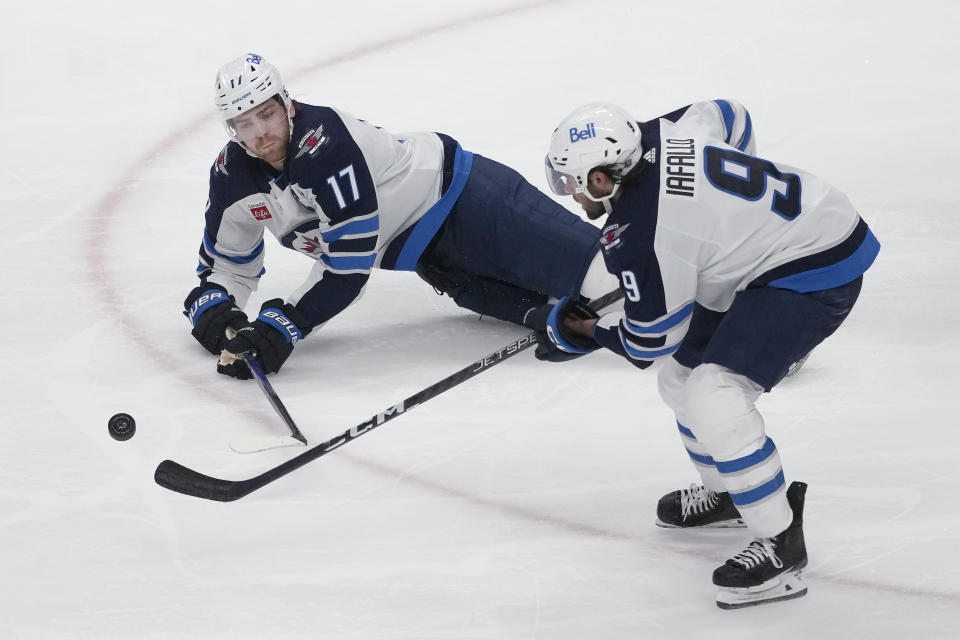 Winnipeg Jets center Adam Lowry (17) passes the puck to left wing Alex Iafallo (9) during the third period of the team's NHL hockey game against the San Jose Sharks in San Jose, Calif., Thursday, Jan. 4, 2024. (AP Photo/Jeff Chiu)