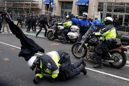 File Photo: A police officer falls to the ground as another shoots pepper spray at protesters demonstrating against U.S. President Donald Trump on the sidelines of the inauguration in Washington, D.C. January 20, 2017. REUTERS/Adrees Latif/File Photo