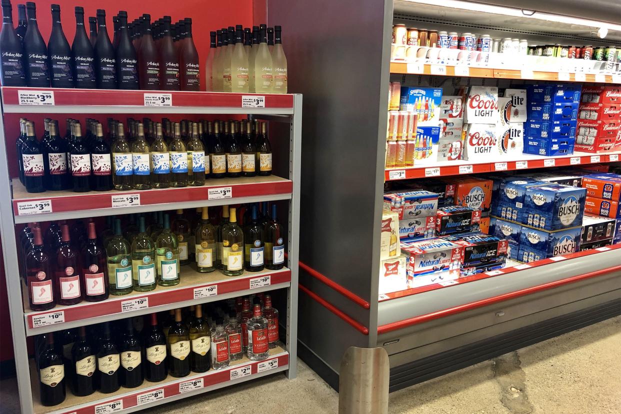 Alcohol section of Save A Lot, wine and few spirits on four shelves on left side, beer on three shelves in cooler on right side