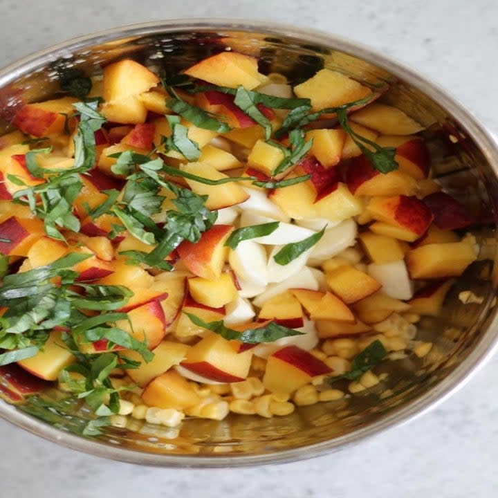 Chopped peaches, mozzarella, and basil in a bowl.