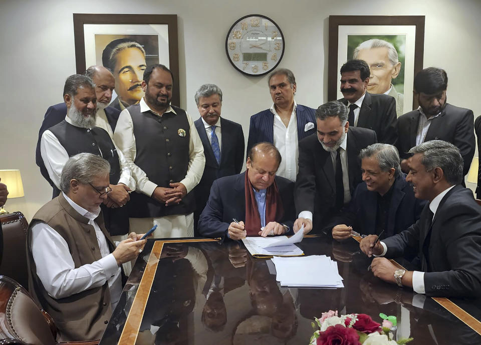 In this released by Pakistan Muslim League-N Party, Pakistan's former Prime Minister Nawaz Sharif, centre, signs on the documents upon his arrival at Islamabad airport, Islamabad, Pakistan, on Saturday, Oct. 21, 2023. (Muslim League-N Party via AP)