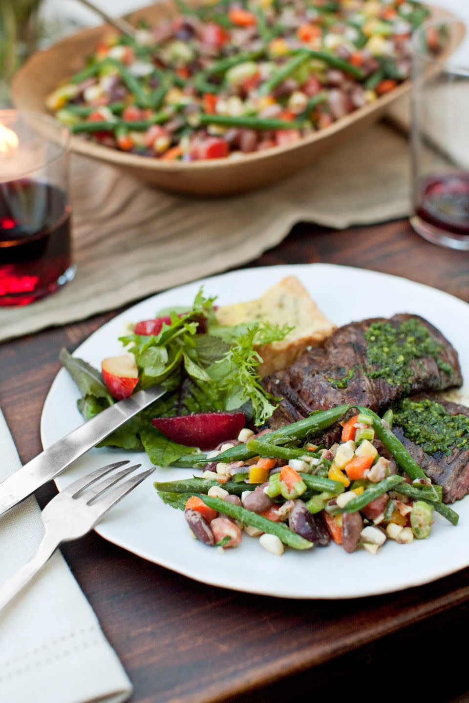 grilled skirt steak with red wine chimichurri served with salad and vegetables on a white plate