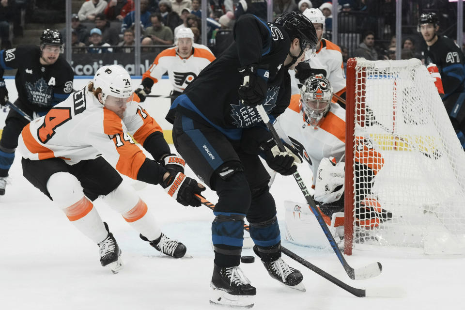 Philadelphia Flyers goaltender Carter Hart (79) watches for the puck as Toronto Maple Leafs center Alexander Kerfoot (15) and Flyers right wing Owen Tippett (74) battle at the side of the net during the second period of an NHL hockey game, Thursday, Dec. 22, 2022 in Toronto. (Chris Young/The Canadian Press via AP)