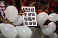 A woman holds a poster composed with images of the 10 teenage players killed by a fire at the Flamengo training center last Friday, at the Maracana Stadium, in Rio de Janeiro, Brazil, Thursday, Feb. 14, 2019, ahead of a soccer match between Flamengo and Fluminense. (AP Photo/Leo Correa)