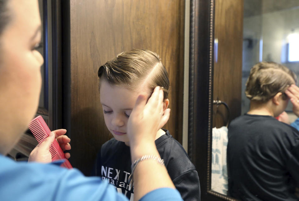 Linda Davila-Macal combs her son's hair Andres at home on Monday, Aug. 31, 2020 in Edinburg, Texas. Like educators across the nation, Davila-Macal is trying to adjust to a completely online learning curriculum. In addition, like parents across the nation, she's trying to adjust to her children attending school from home(Delcia Lopez/The Monitor via AP)