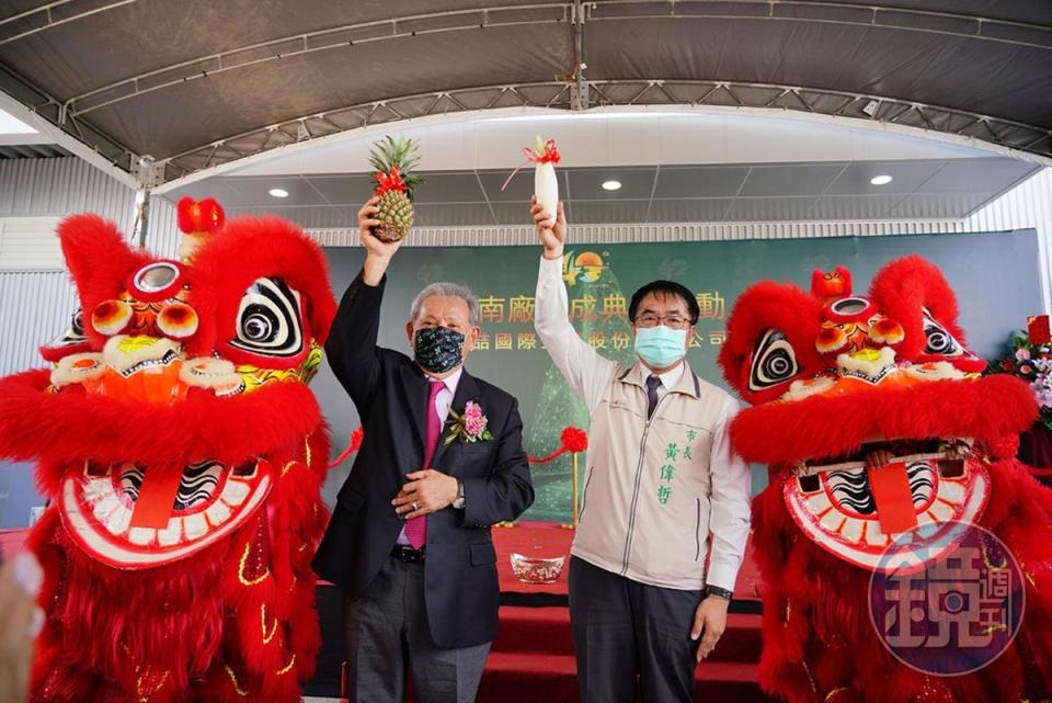 美喆台南新廠落成，董事長陳本源（左）與台南市長黃偉哲高舉鳳梨與菜頭（白蘿蔔）要取得好彩頭。