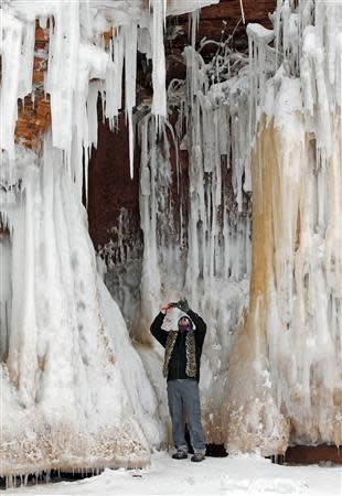 A man photographs ice formations on a rock face at the Apostle Islands National Lakeshore of Lake Superior near Cornucopia, Wisconsin February 15, 2014. REUTERS/Eric Miller