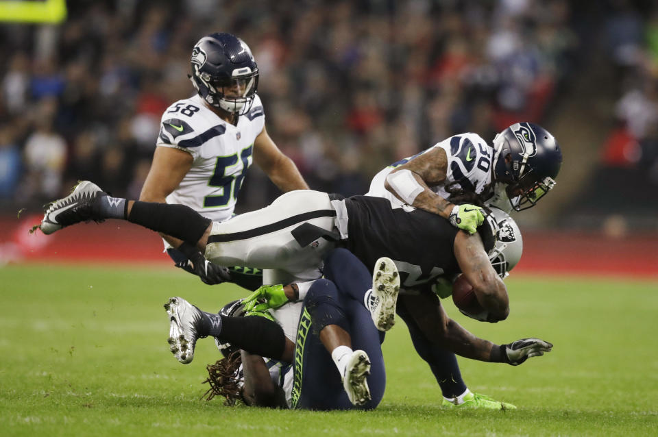 Oakland Raiders running back Marshawn Lynch (24) is halted by the Seattle Seahawks defense during the first half of an NFL football game at Wembley stadium in London, Sunday, Oct. 14, 2018. (AP Photo/Matt Dunham)