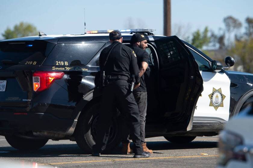 A man is escorted to a sheriff's vehicle after a shooting at the Sacramento Sikh Society Temple, it is unknown if he was involved, on Sunday, March 26, 2023, in Sacramento. The shooting occurred during the Sacramento Sikh Society's first Nagar Kirtan Parade.